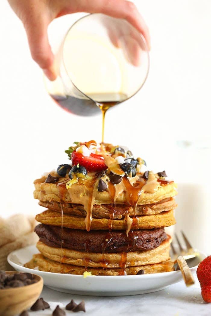 Pouring syrup onto a stack of pancakes