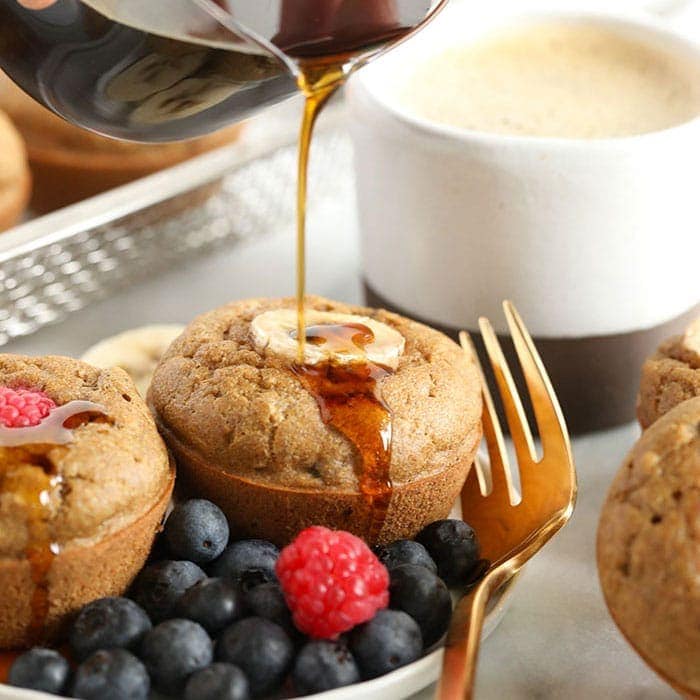 banana pancake muffins being drizzled with maple