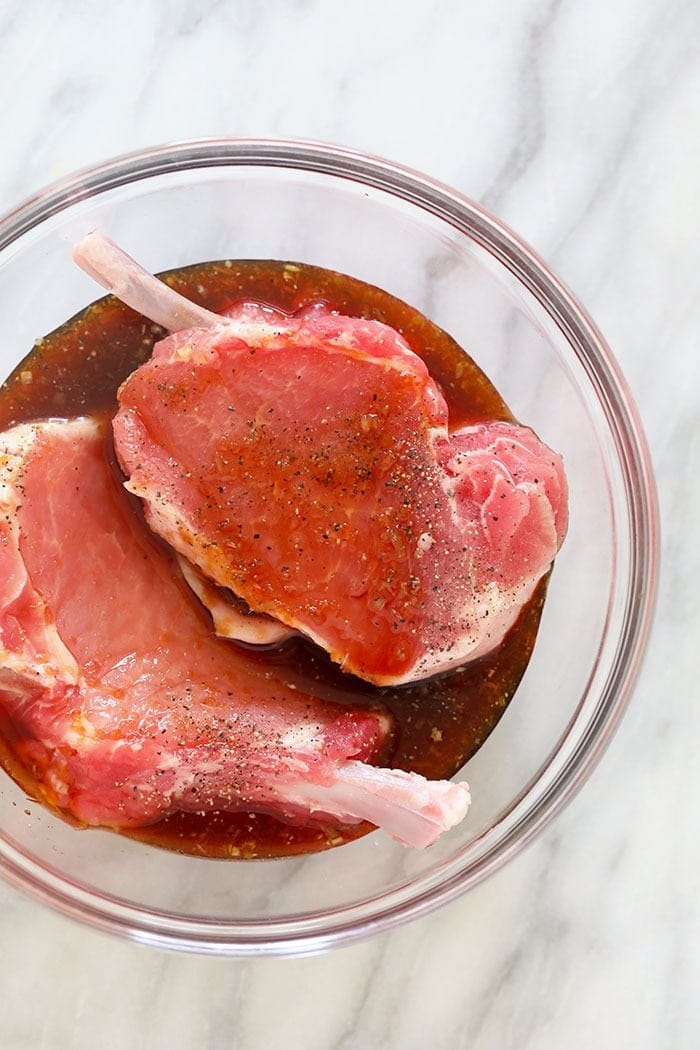 pork chops in marinade in glass bowl