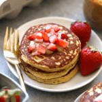 almond flour pancakes topped with strawberries and peanut butter.