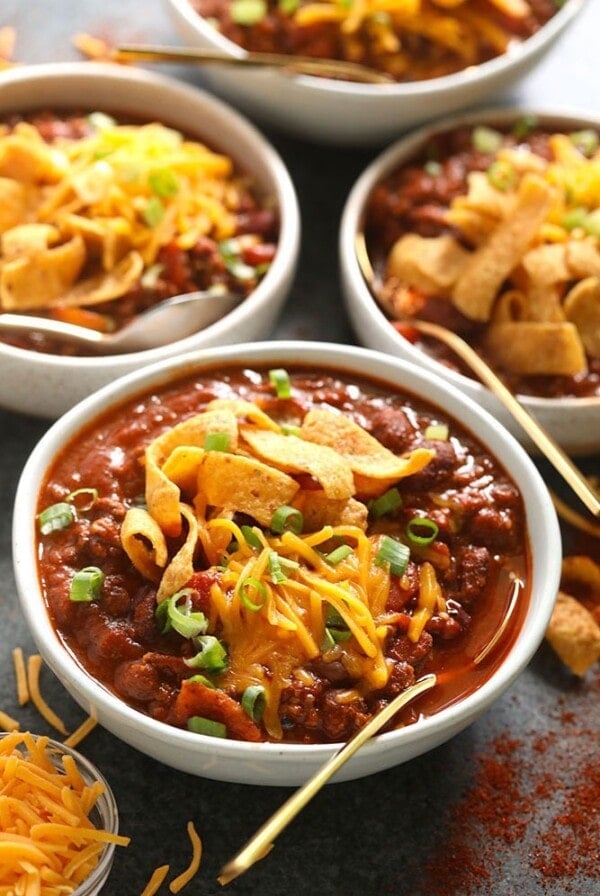 Four bowls of the best chili topped with cheese and served with tortilla chips.
