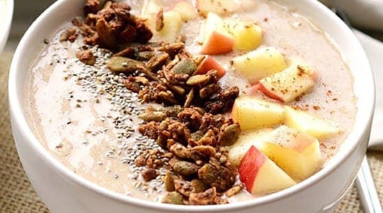 A bowl of oatmeal with apples.