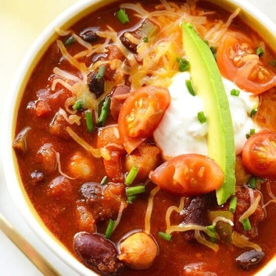 A bowl of vegetarian chili with sour cream and avocado.