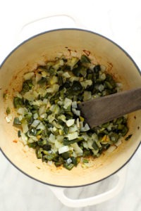 A pot filled with green chili vegetables and a wooden spoon.