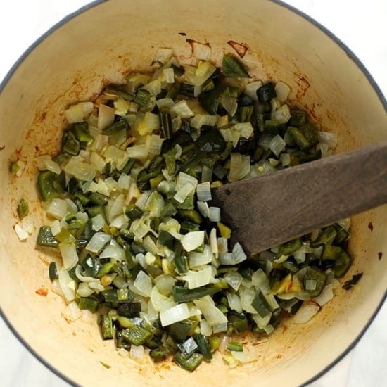 A pot filled with green chili vegetables and a wooden spoon.