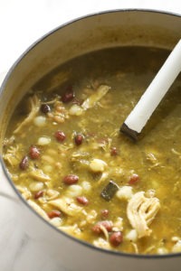 a pot of chicken, bean, and green chili soup with a spoon.