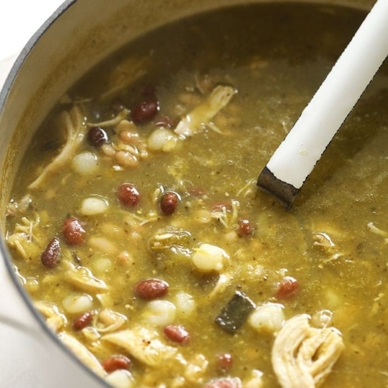 a pot of chicken, bean, and green chili soup with a spoon.
