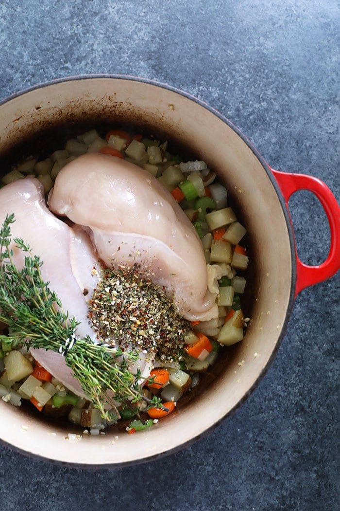 Creamy Chicken Noodle Soup is a healthy dinner idea that the whole family will love. It's packed with tons of protein and veggies and is creamy as can be! vegetables and chicken breast in pot