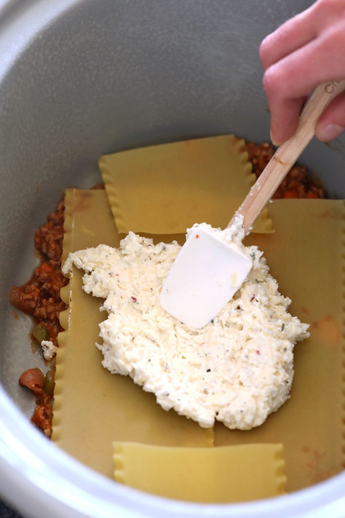 Spreading cheese mixture on lasagna noodles.