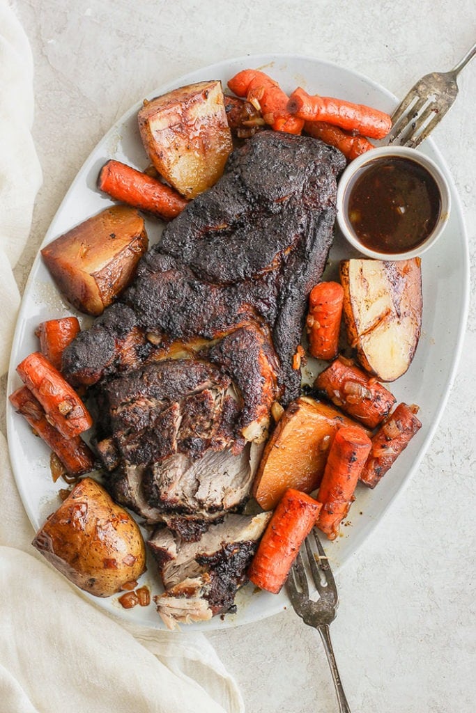 Pork roast on a platter with vegetables.