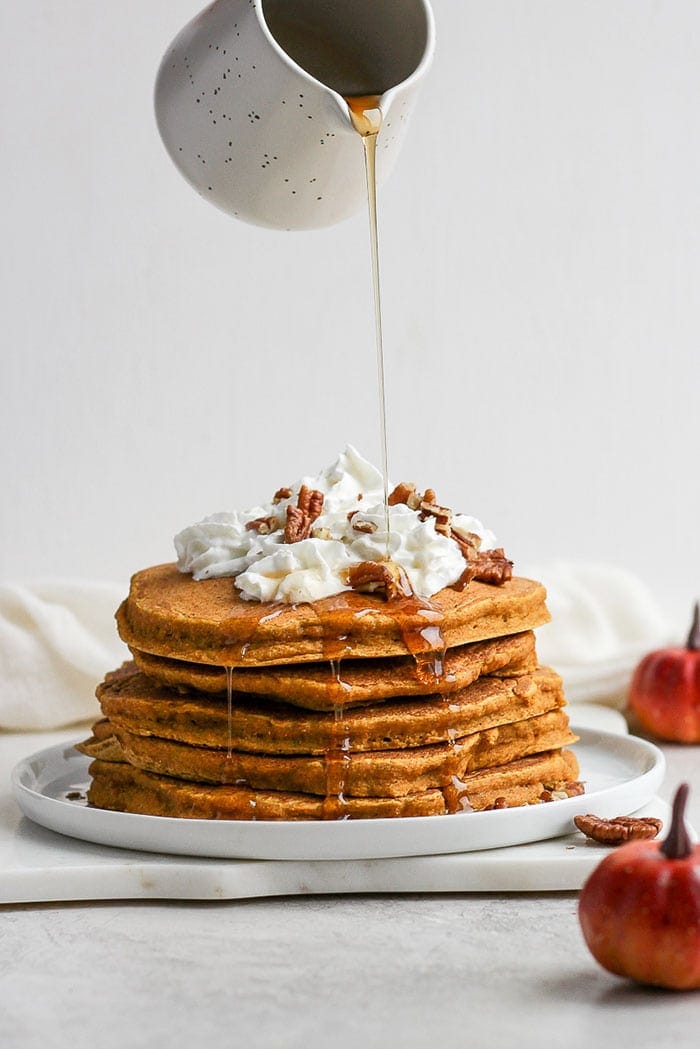 verser du sirop sur des pancakes à la citrouille.