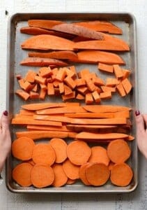 Sweet potatoes cut into a variety of shapes on a baking sheet.