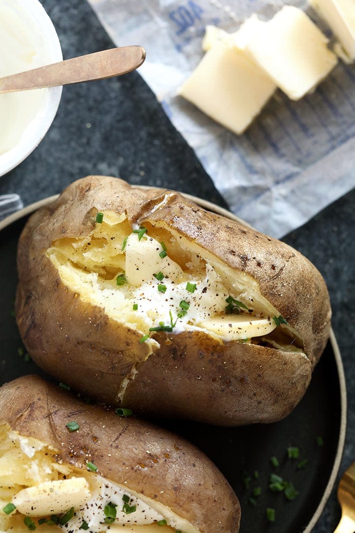 papas al horno con olla de barro cubiertas con cebollino y crema agria