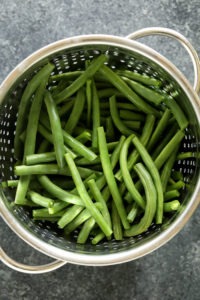 Green beans in a colander, served almondine-style.