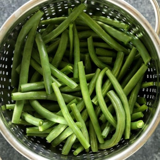 Green beans in a colander, served almondine-style.