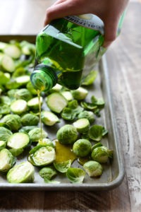 brussel sprouts being drizzled with olive oil