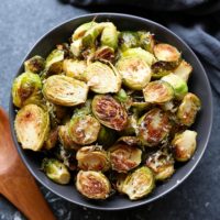 Roasted brussels sprouts with parmesan, served in a black bowl.