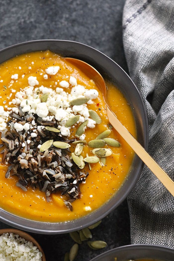 instant pot butternut squash soup in a bowl topped with goat cheese and wild rice and pepitas