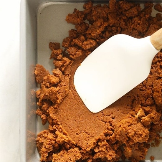 a white spatula is being used to mix the ingredients for pumpkin cheesecake bars in a baking pan.