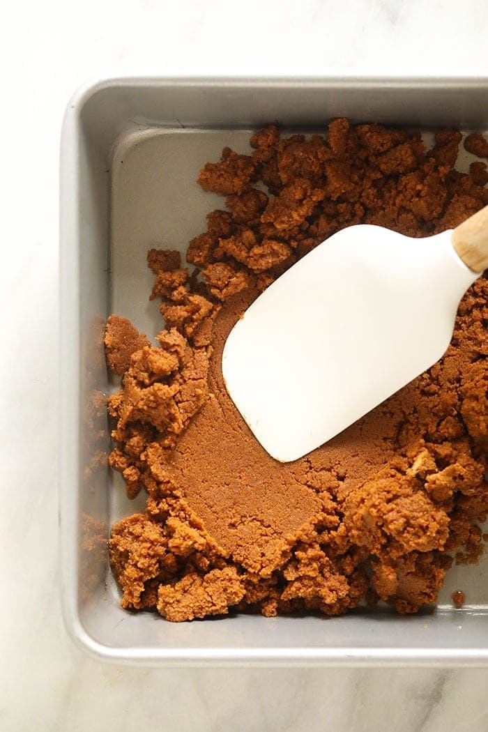 pumpkin cheesecake bar crust being pressed into a pan