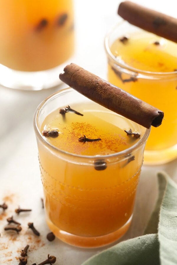 two glasses of apple cider with cinnamon sticks.