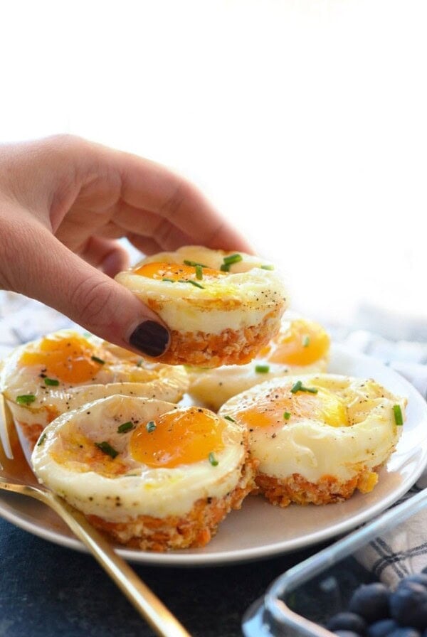 A person holding up a plate of Sweet Potato Hash Egg Cups on a plate.