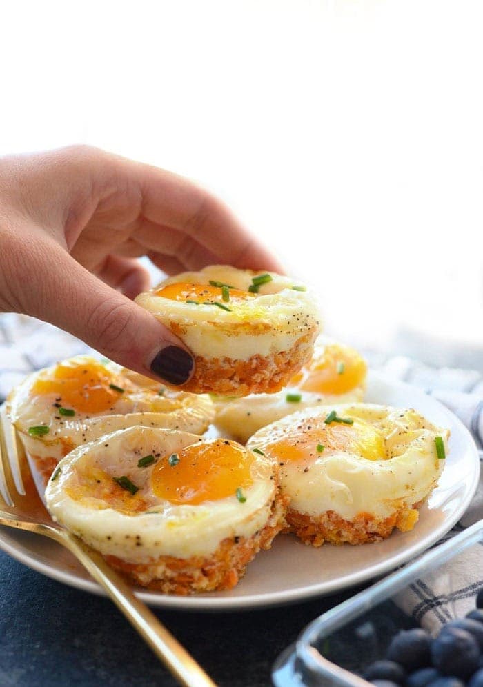 A person holding up a plate of Sweet Potato Hash Egg Cups on a plate.