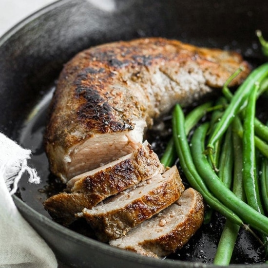 Sous vide pork tenderloin with green beans cooked in a skillet.