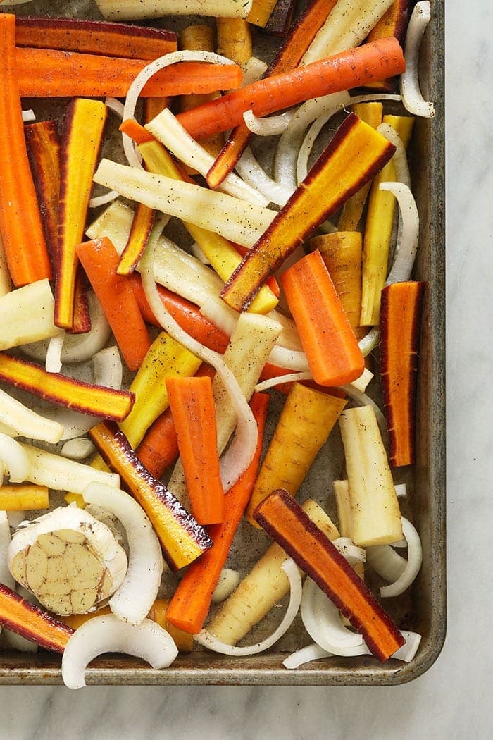 fresh cut carrots and onions on a baking tray
