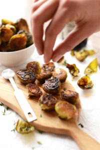 Roasted brussel sprouts on a wooden cutting board.