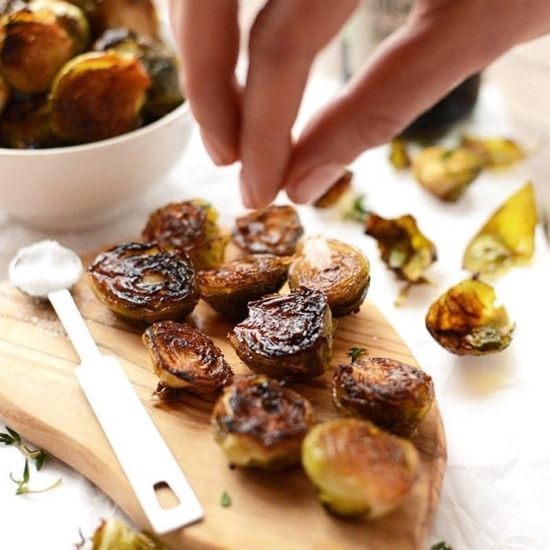 Roasted brussel sprouts on a wooden cutting board.