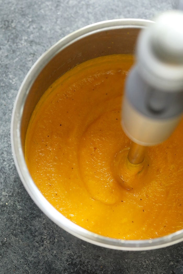 butternut squash soup being pureed with an emulsifier blender