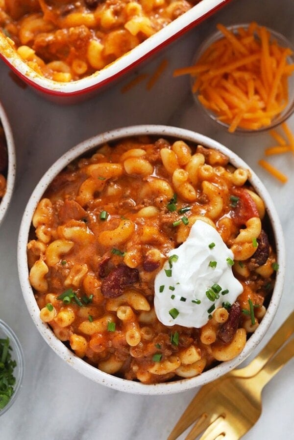 Two bowls of chili mac and cheese topped with sour cream.