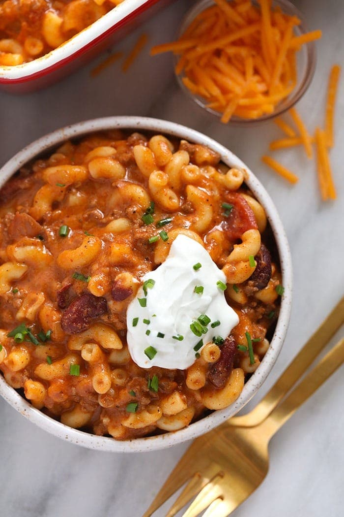 Chili mac and cheese might be the best dinner of all time. Make it once and eat it all week long. Bonus, it's kid-friendly and protein-packed! Chili mac in a bowl with greek yogurt scooped on top