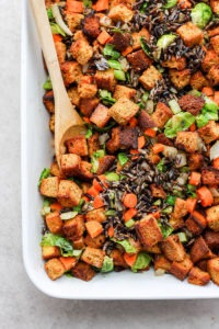 A dish of cornbread dressing with carrots and brussels sprouts.