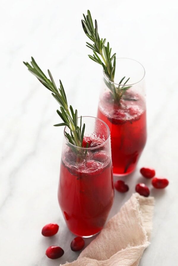 Two glasses with cranberry juice and rosemary sprigs.