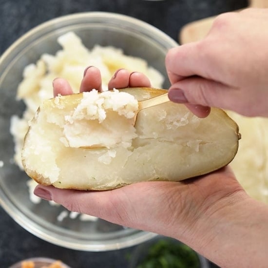 A person slices a potato with a knife to prepare twice baked potatoes.