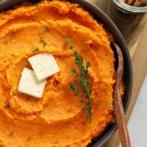 a bowl of mashed sweet potatoes with butter and thyme.