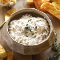 a bowl of Caramelized Onion Dip with bread and croutons.