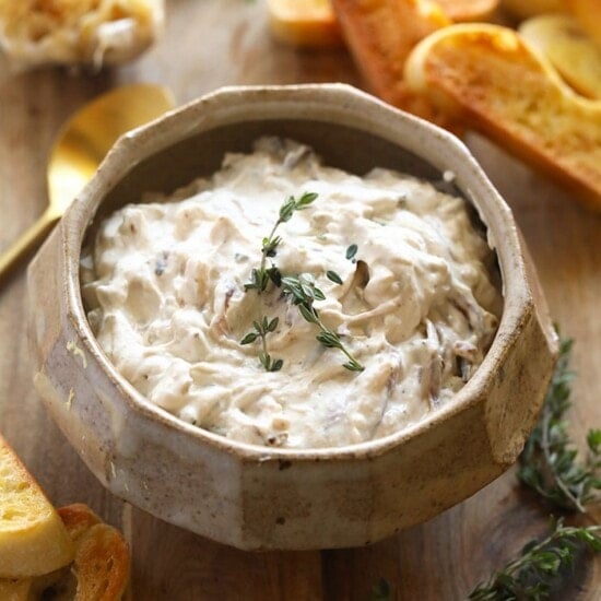 a bowl of Caramelized Onion Dip with bread and croutons.