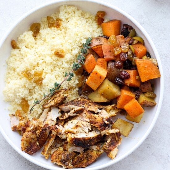 Moroccan chicken served over a bed of couscous and topped with vegetables.