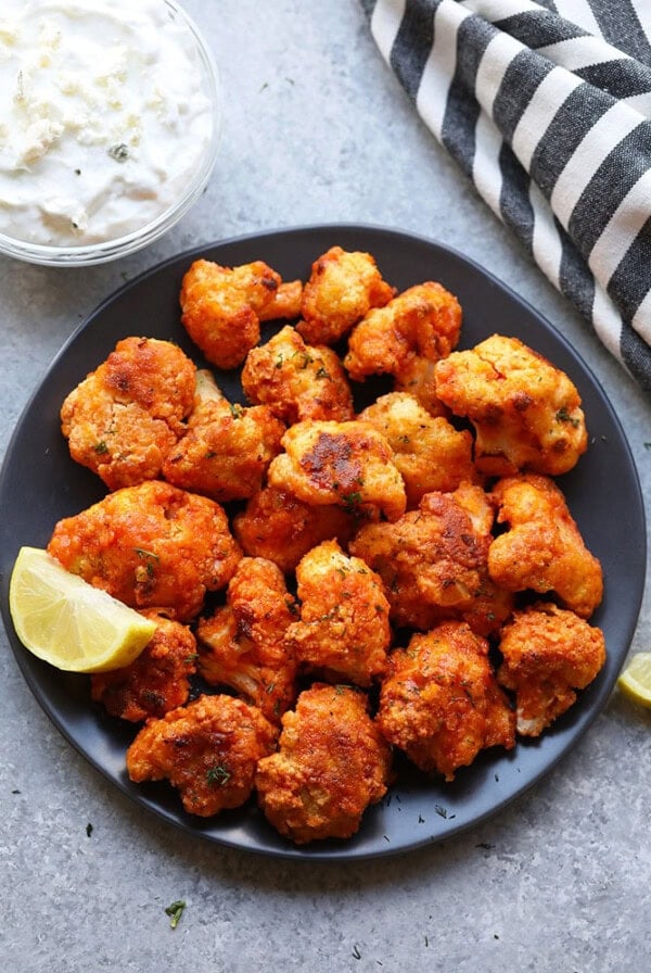Fried cauliflower wings with tzatziki sauce on a plate.