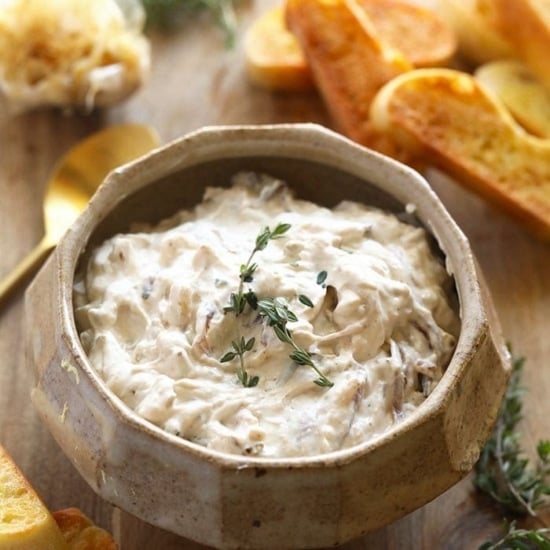 a bowl of caramelized onion dip with bread and thyme.