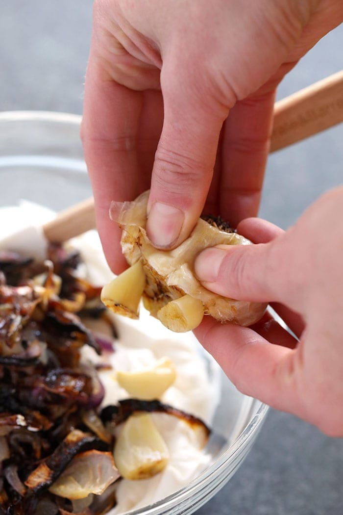 Squeezing roasted garlic into a dip
