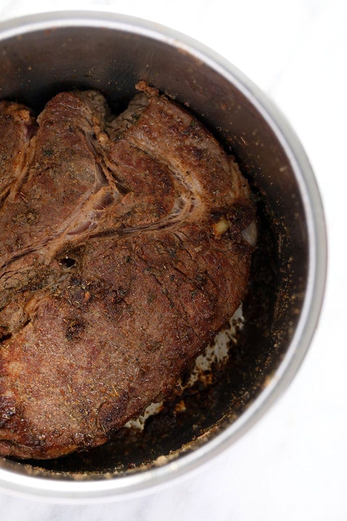 chuck roast being seared in the instant pot prior to pressure cooking