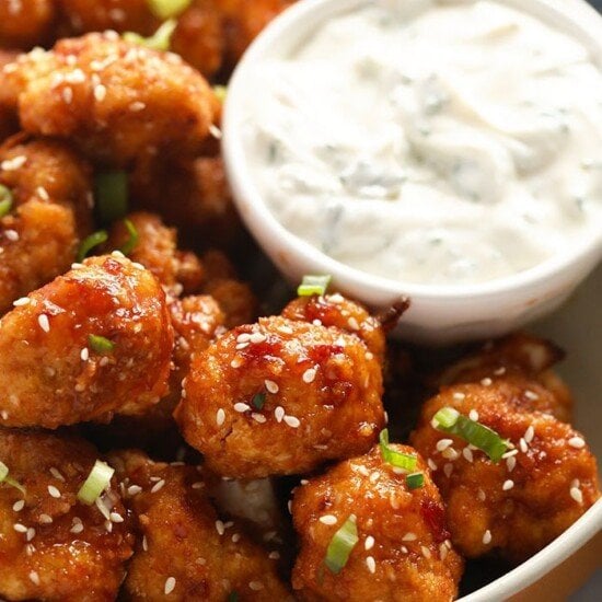 a bowl of cauliflower wings with a side of dipping sauce.