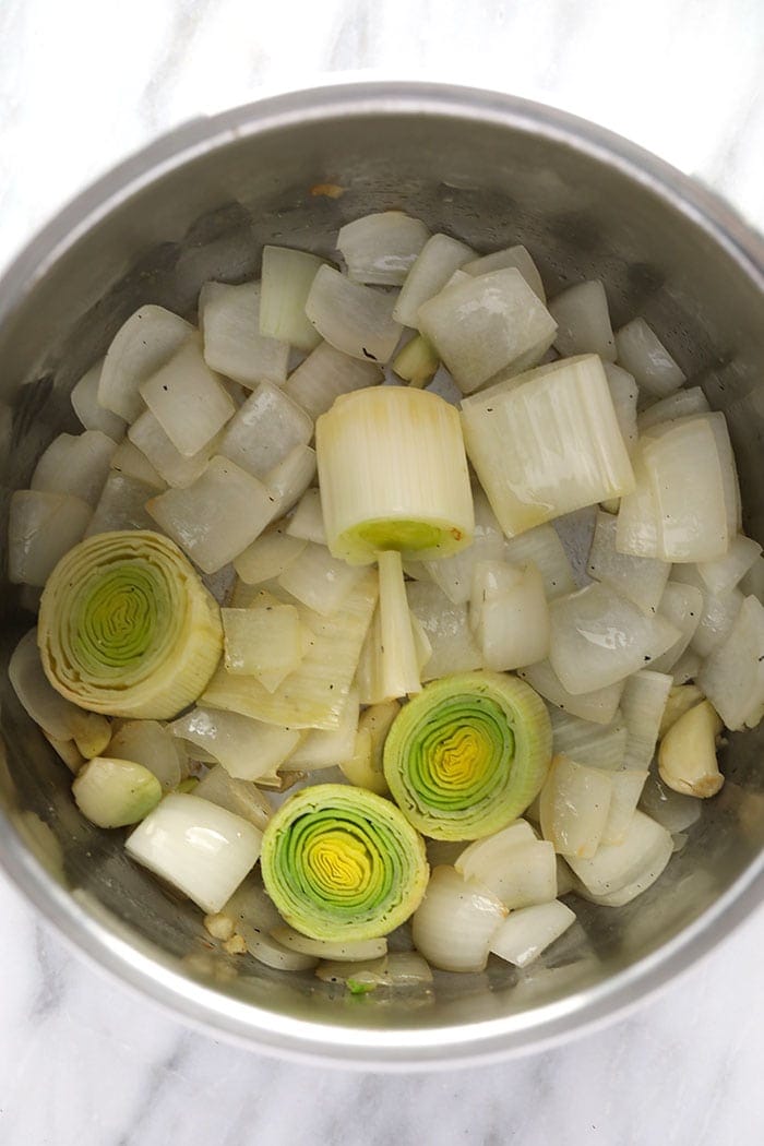 onions, leeks and garlic cloves being sautéed in the instant pot 