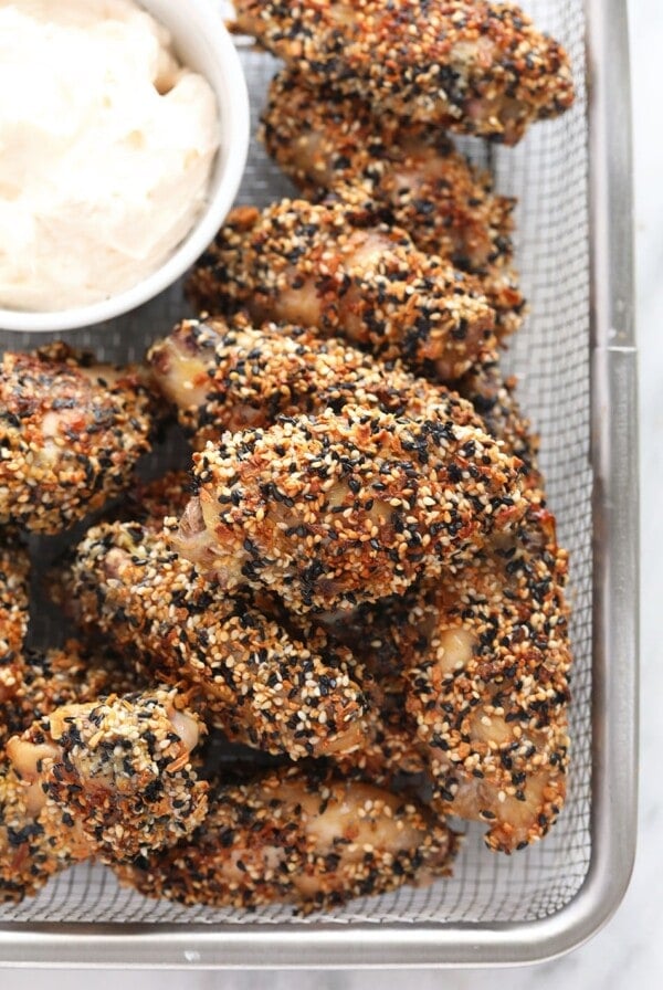 Crispy baked sesame chicken wings with a side of dipping sauce.