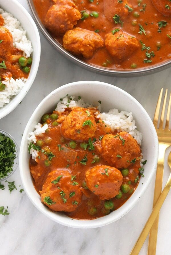 Chicken tikka masala meatballs served with rice and peas in a bowl.