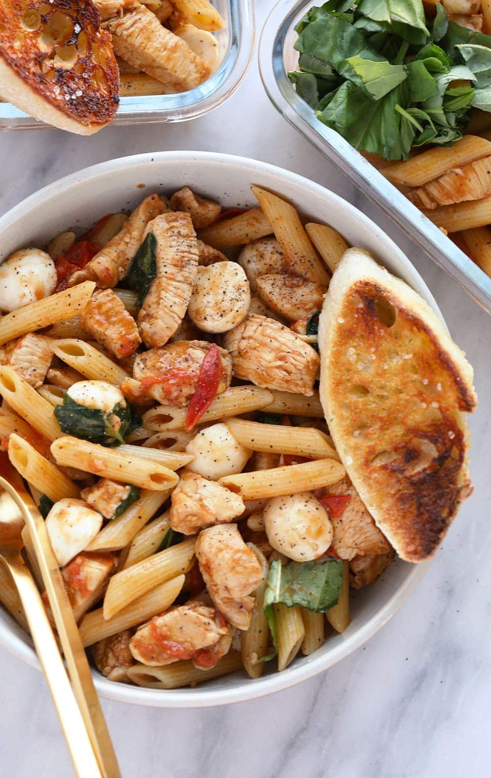  pasta de pollo caprese saludable en un tazón servido con una rebanada de pan francés